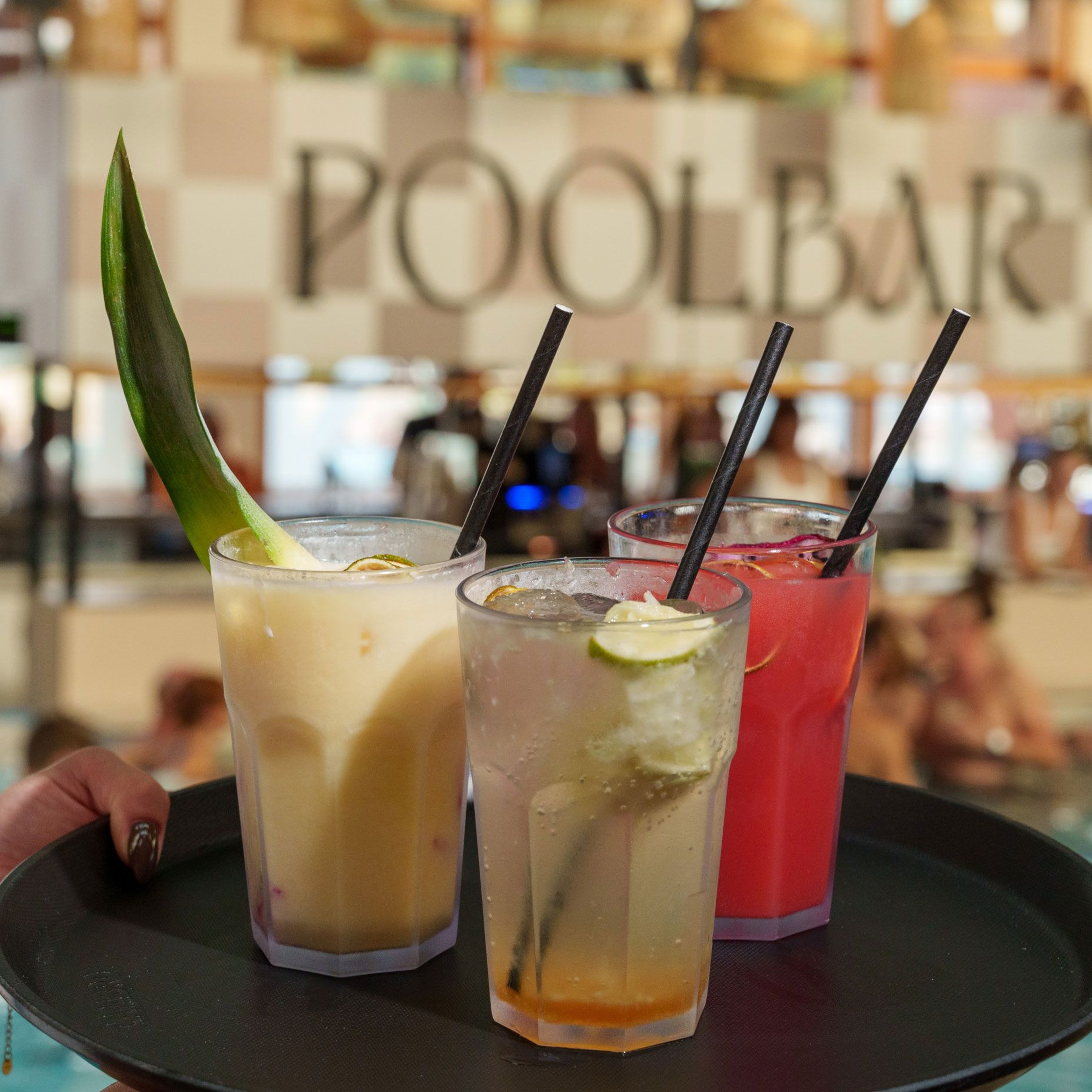 Delicious cocktails on a tray and the pool bar at Thermenresort Loipersdorf in the background.