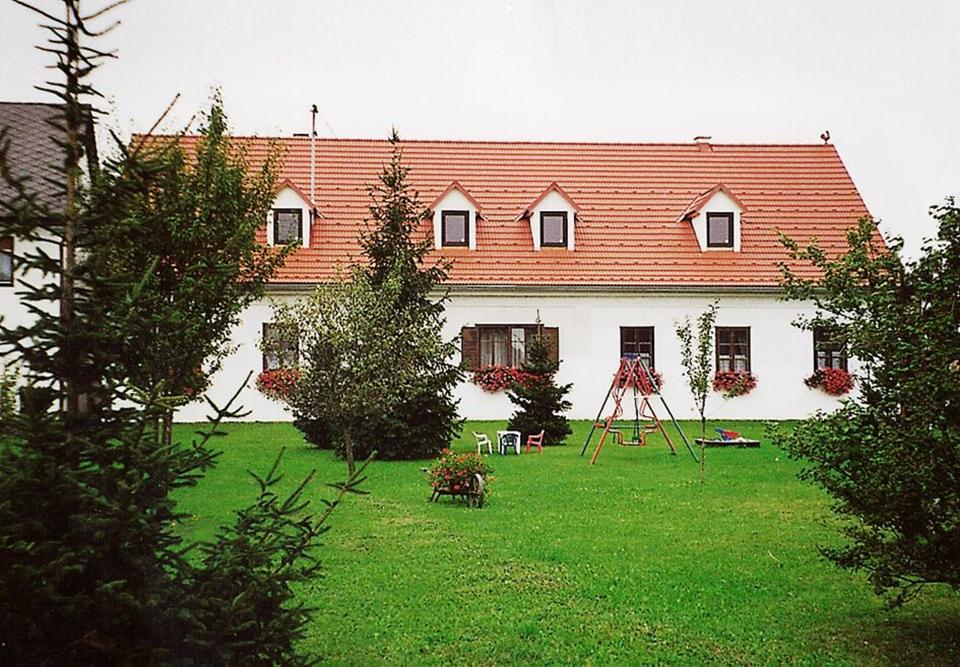 Das Gästehaus Brückler von außen mit Garten und Spielplatz.