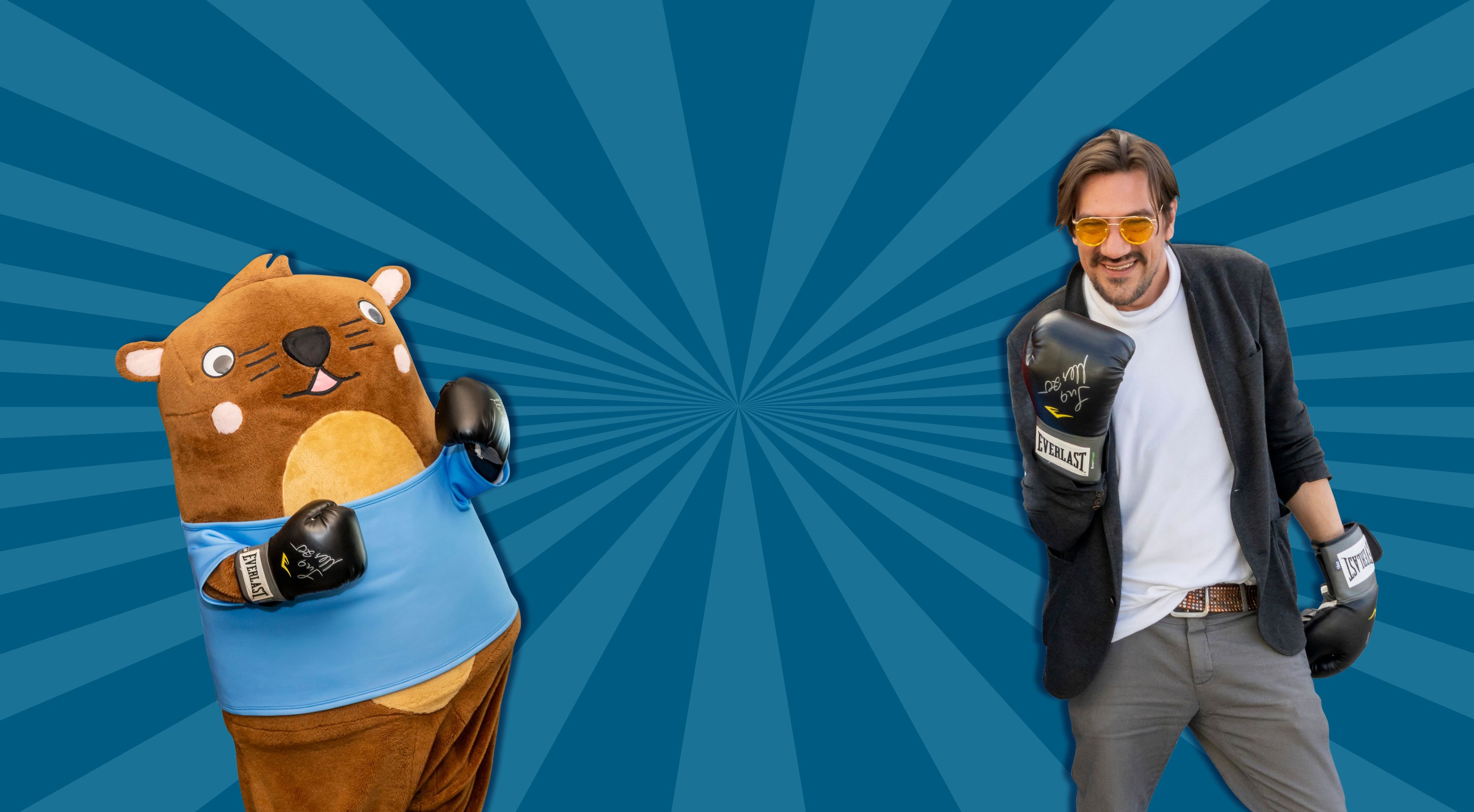 Maskottchen Otto steht mit Boxhandschuhen neben Stani von der Band Alle Achtung. 