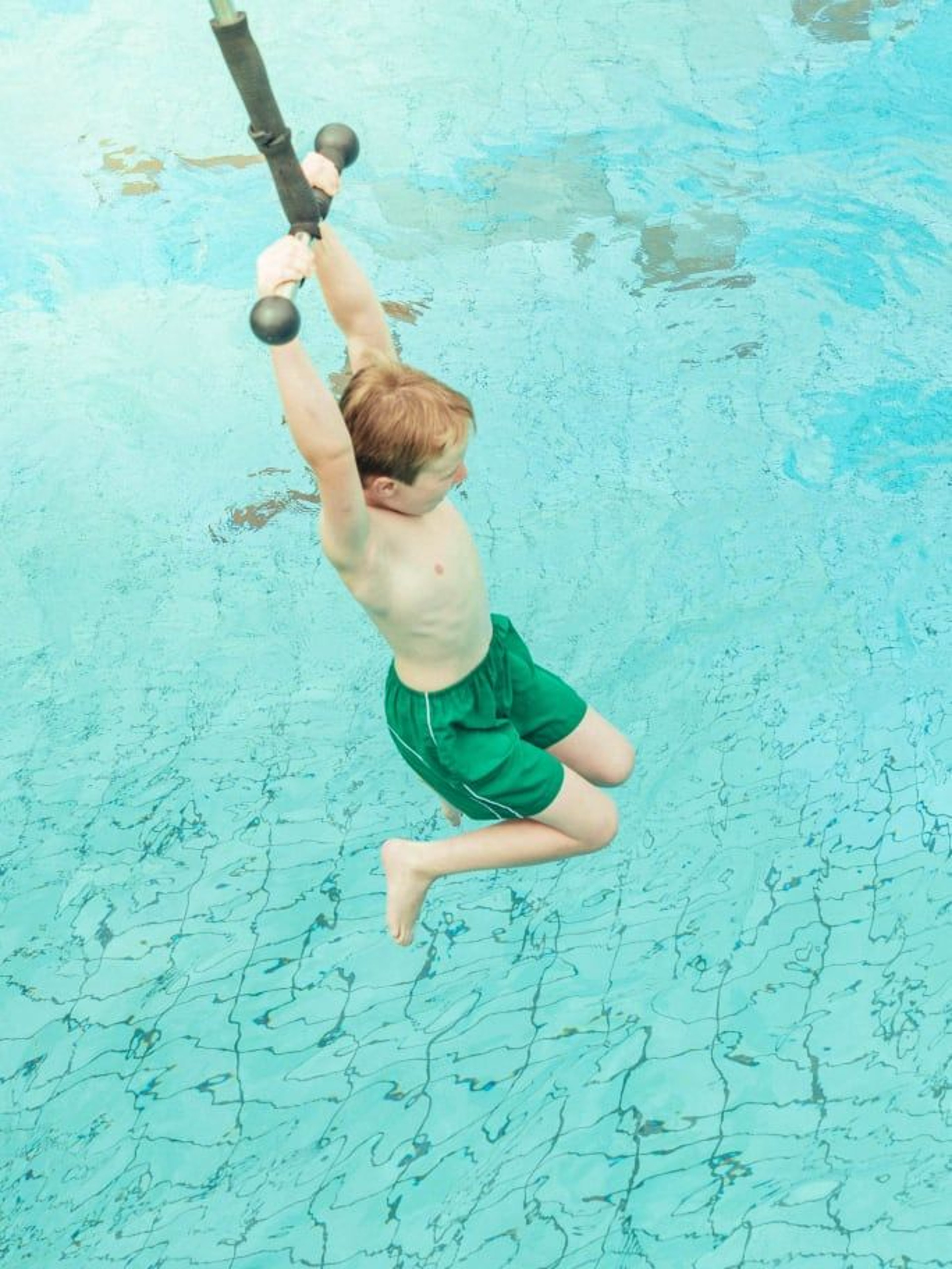 Kind schwingt an der Affenschaukel übers Wellenbecken