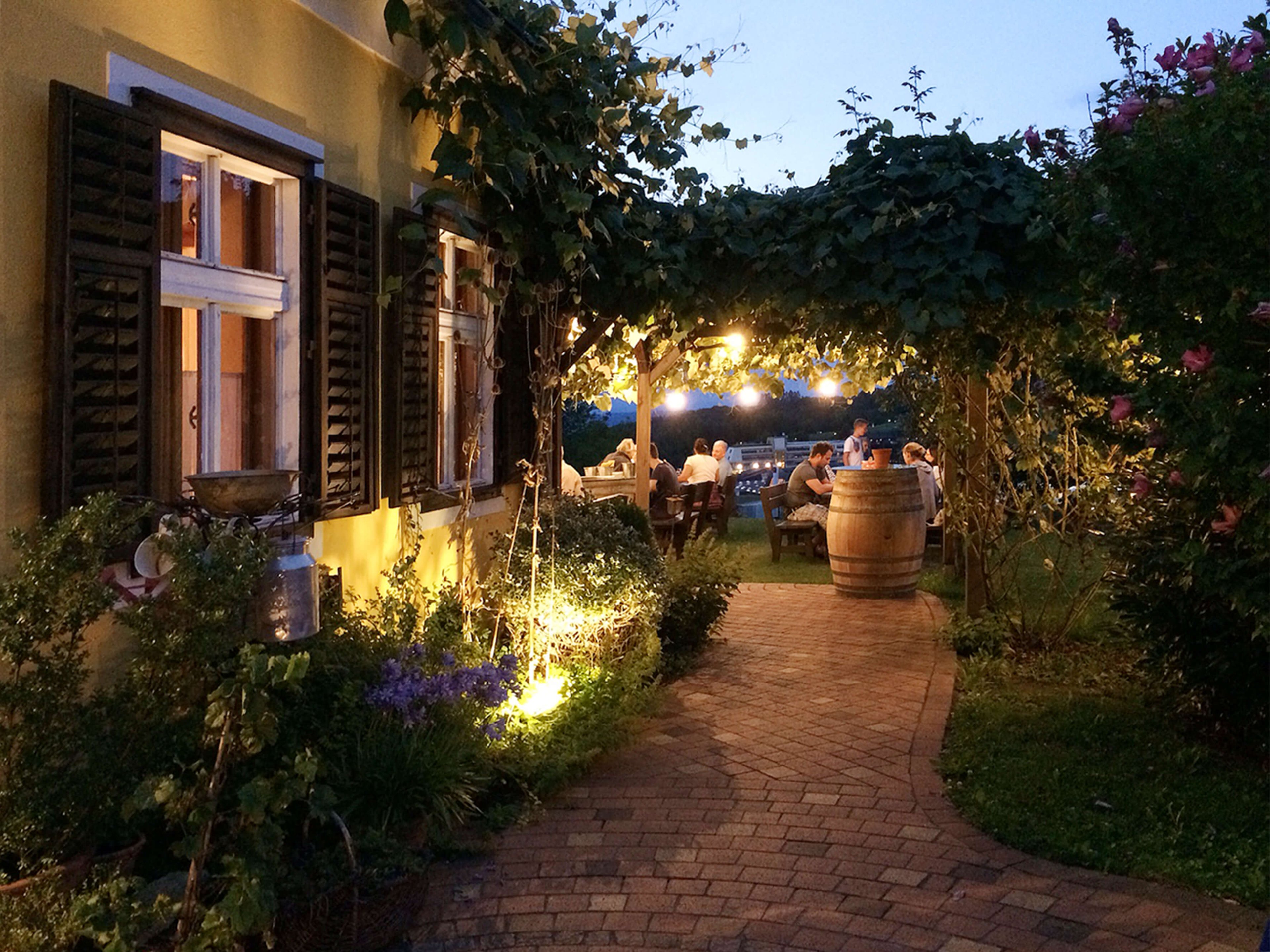 The way to the cozy guest garden in the evening of the Thermenheurigen Kropf.