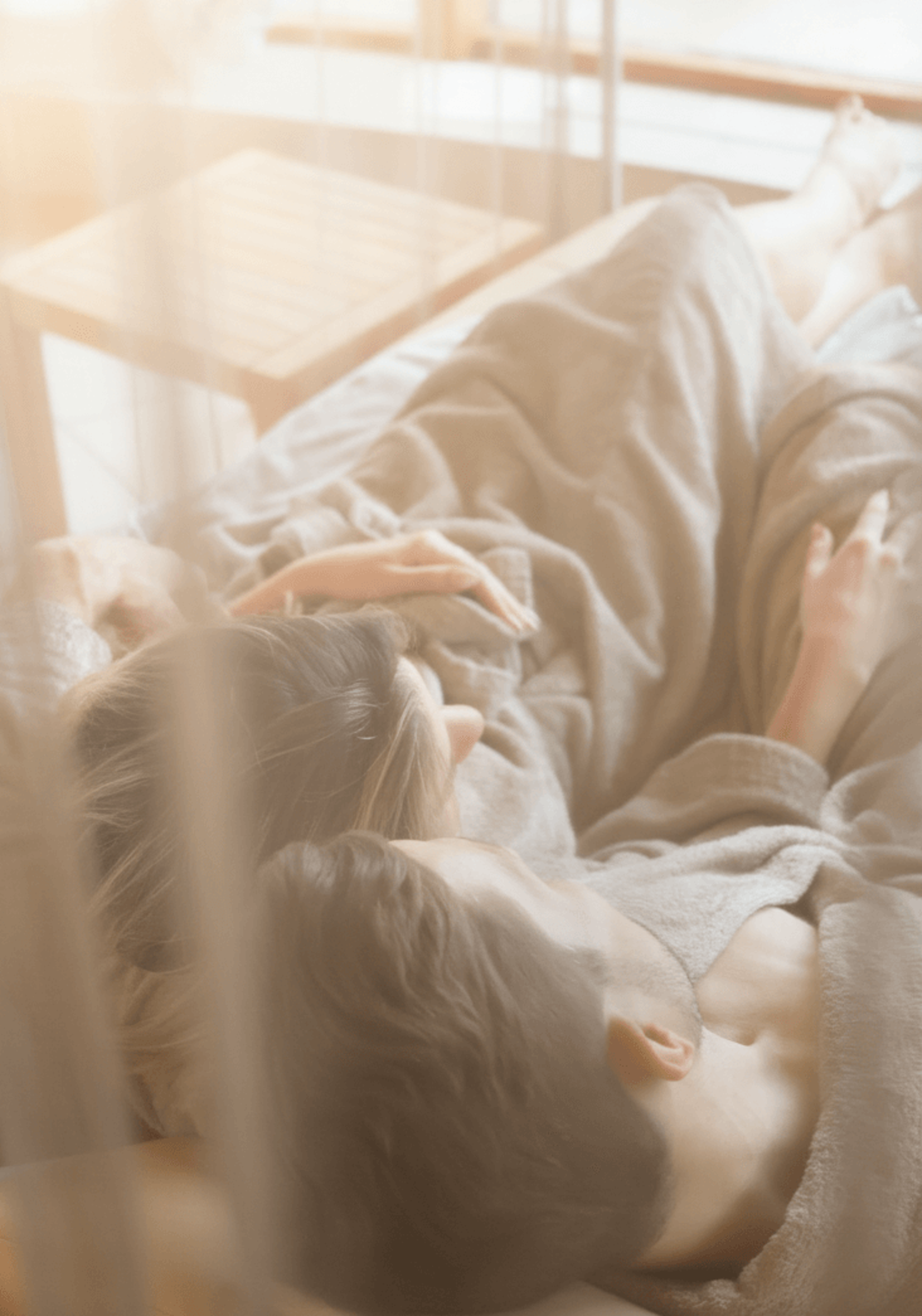 Paar liegt entspannt nebeneinander auf einer Liege, umgeben von sanftem Licht und Vorhängen