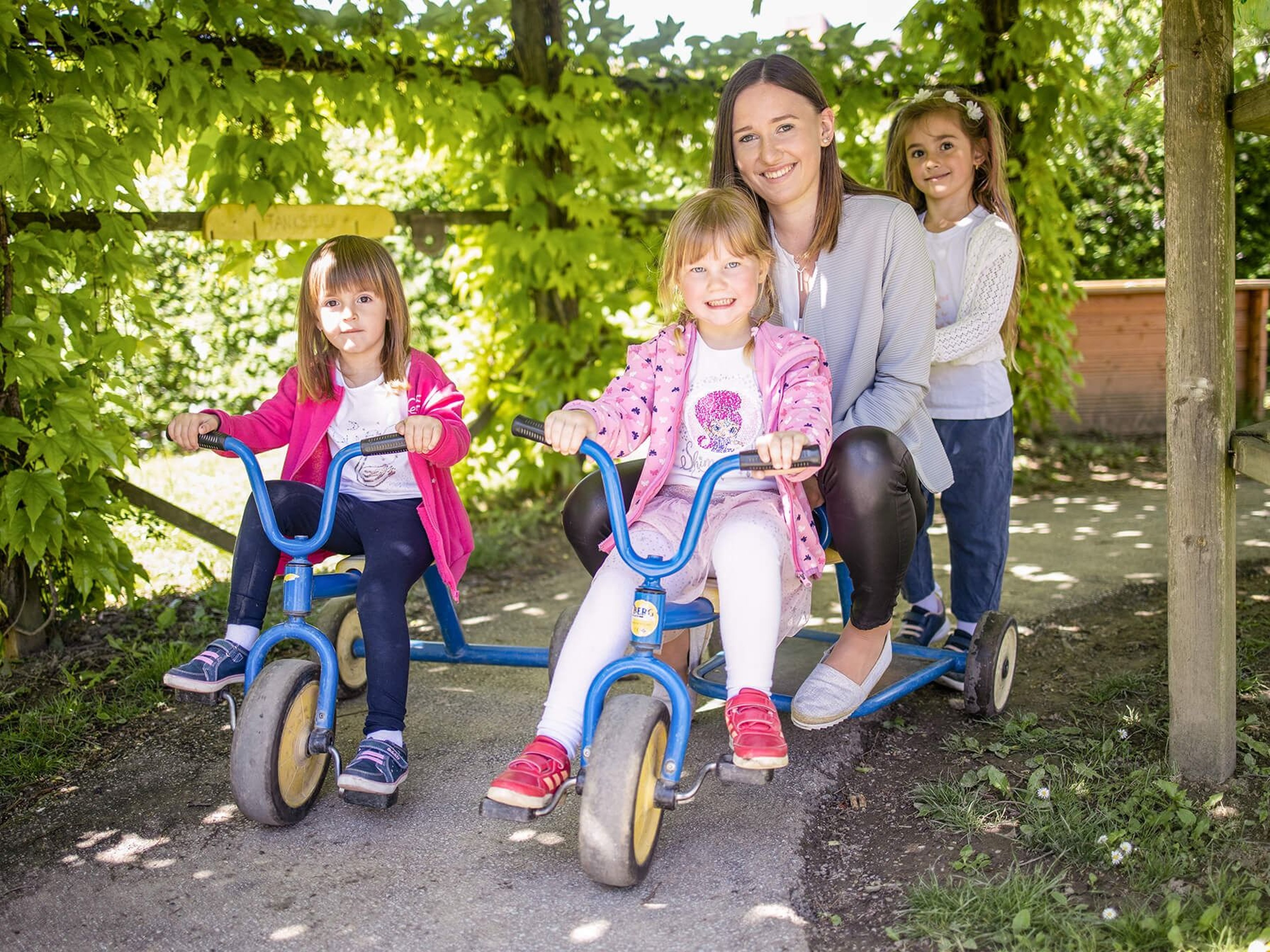 The children from the tourist kindergarten ride a tricycle.