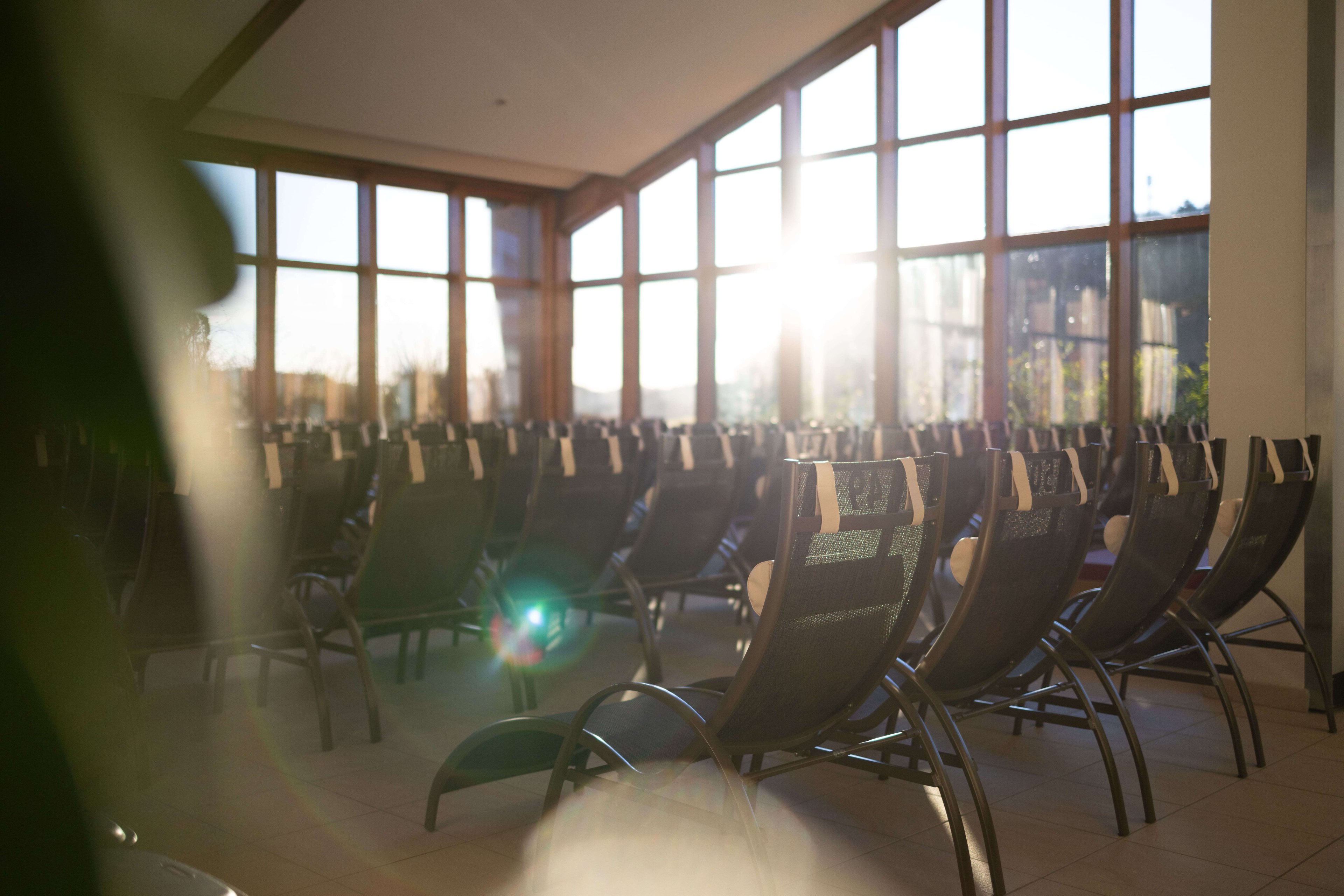 Ansicht Rückseite der Liegen im Thermenbad. Sonne reflekiert durch die Fensterfront.