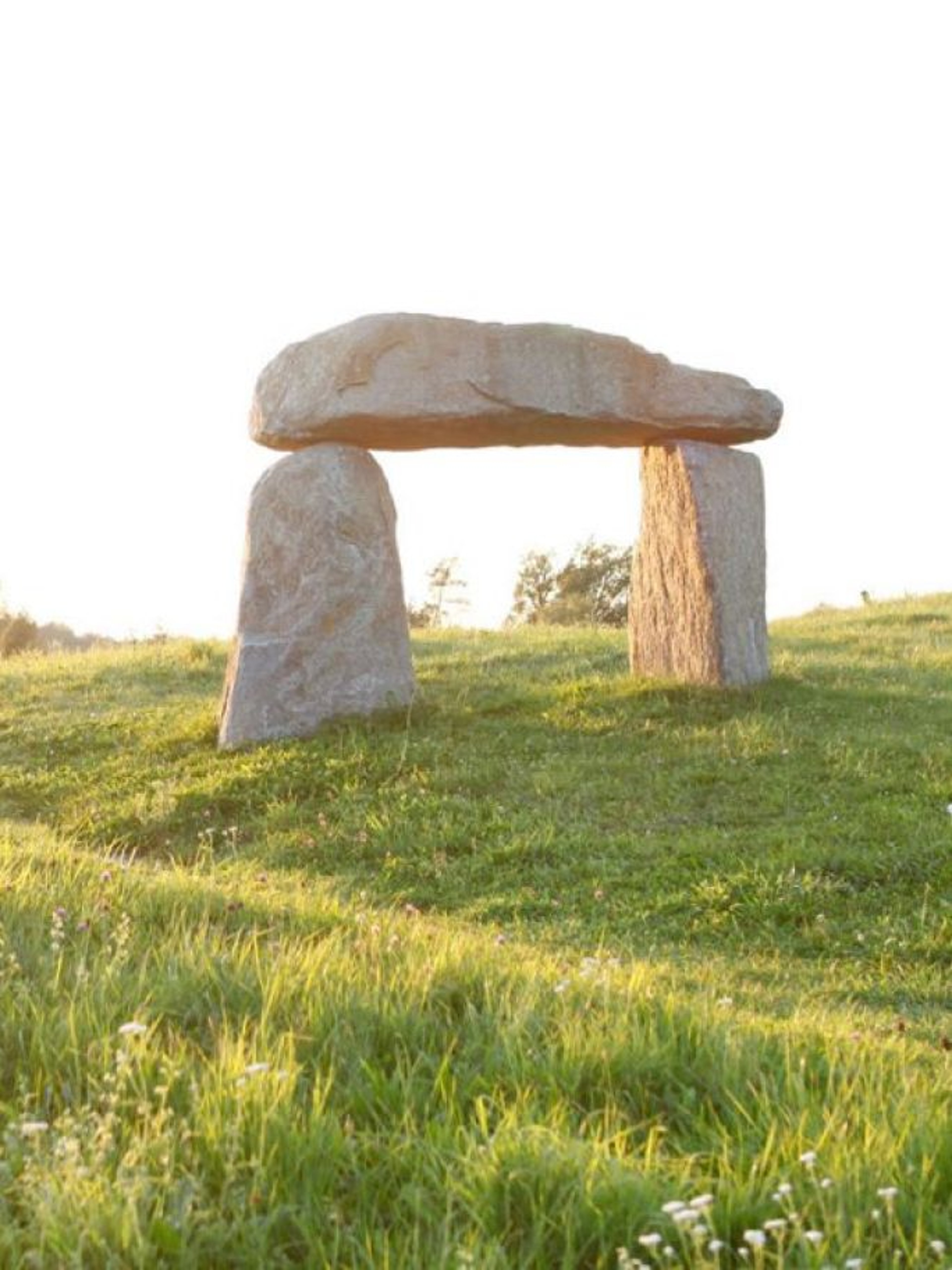 Ein Steinbogen inmitten grüner Hügel.