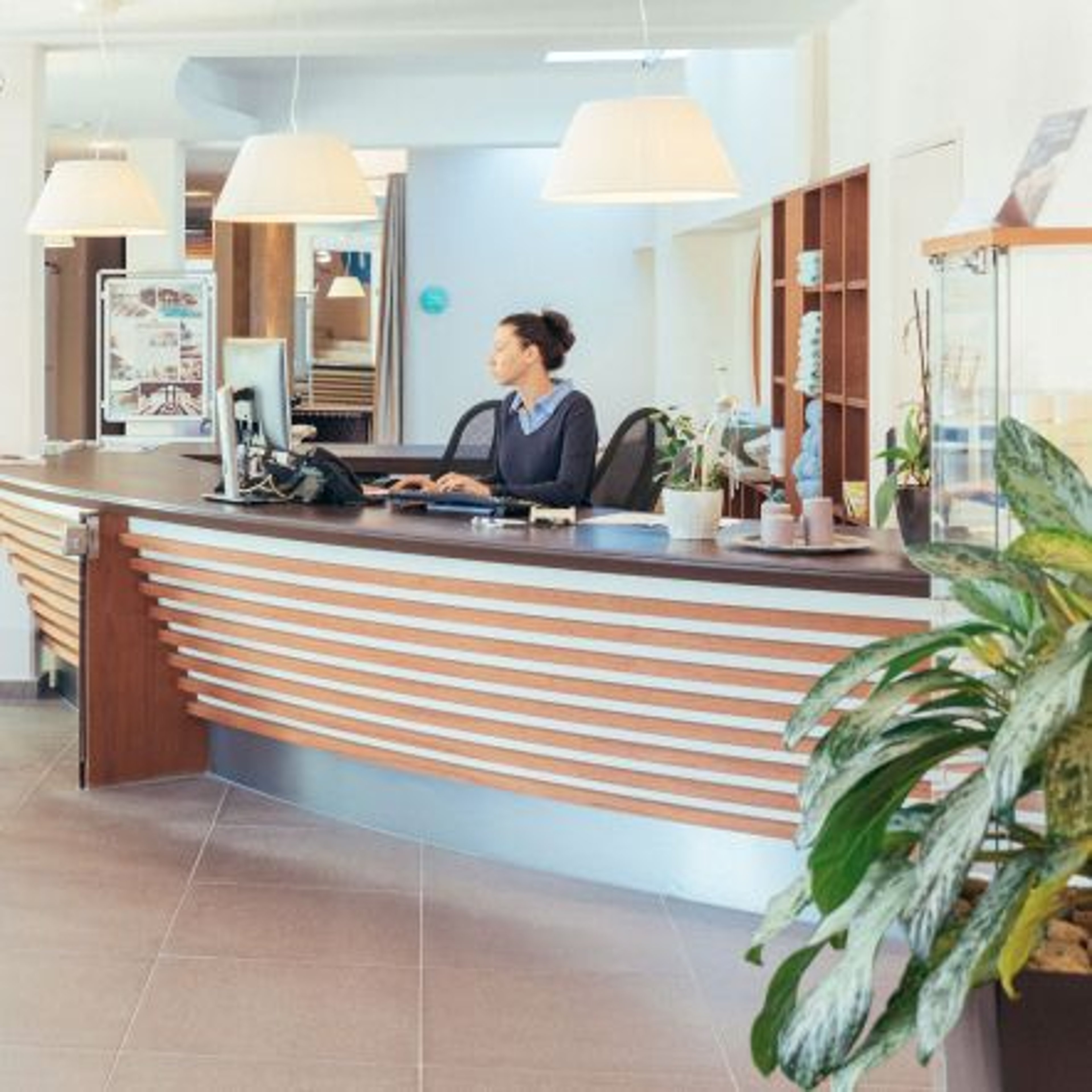 Eine Dame arbeitet an der Rezeption des Thermenresorts Loipersdorf.
