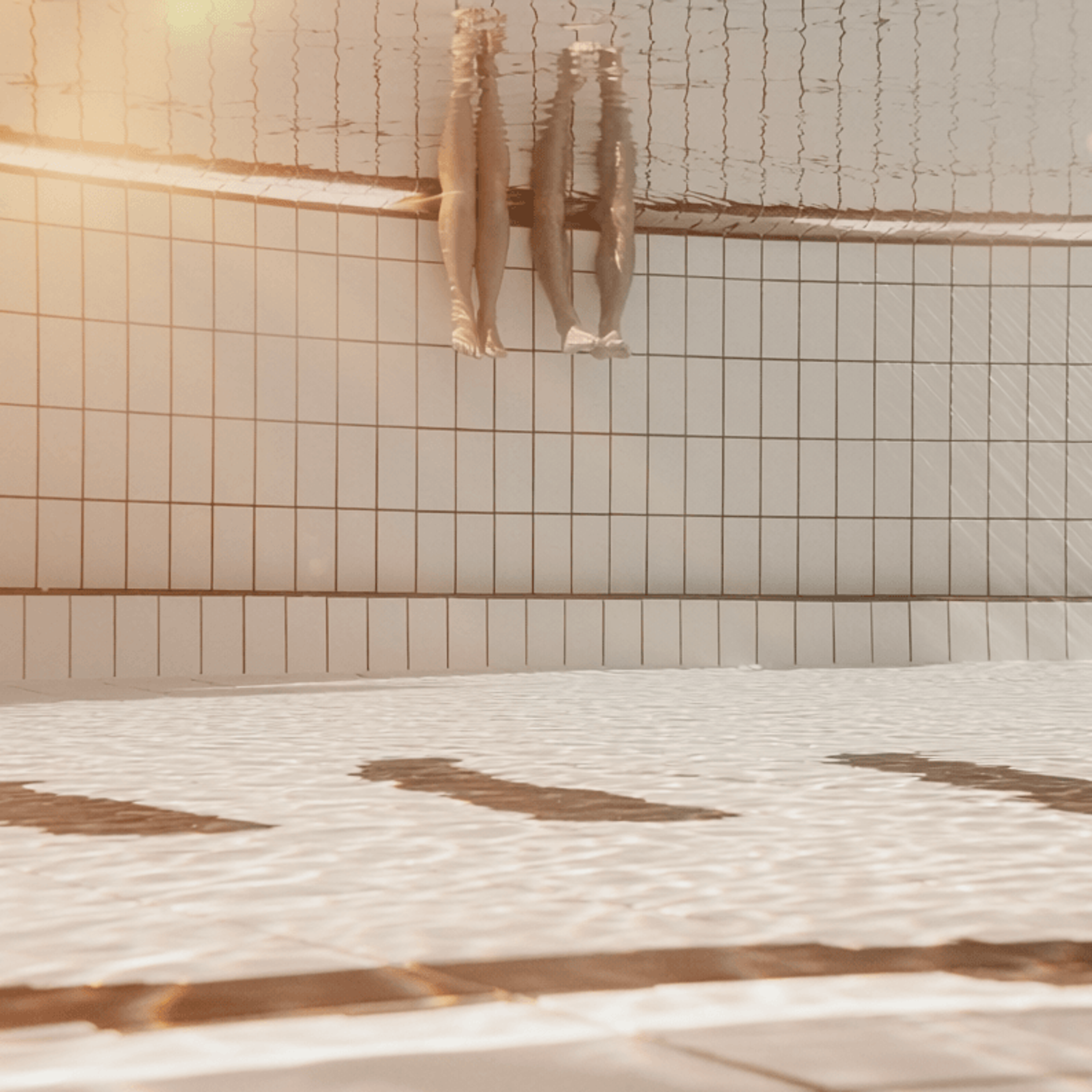 Two people are dipping their legs in the water.