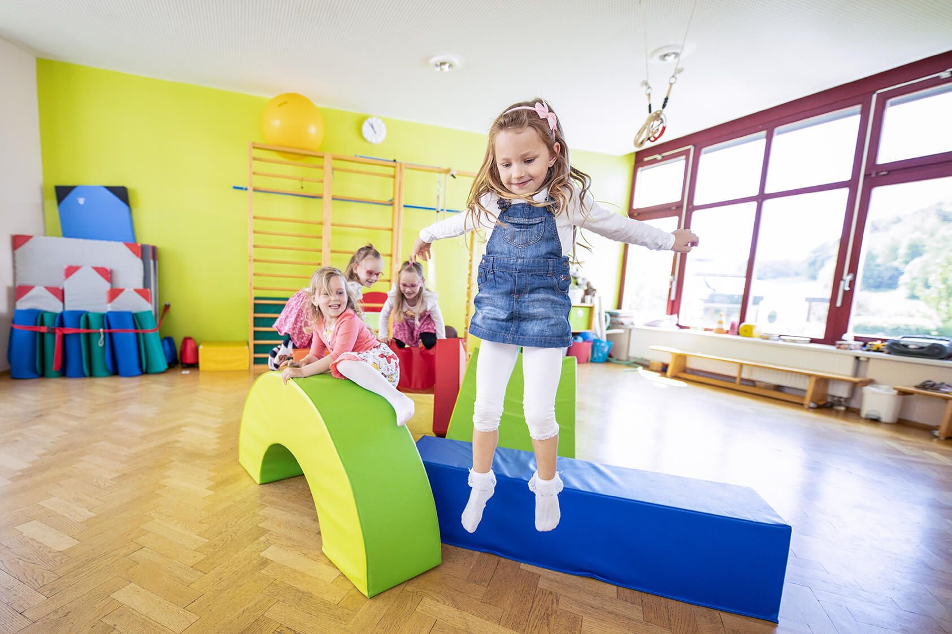 The children from the tourist kindergarten jump over obstacles.
