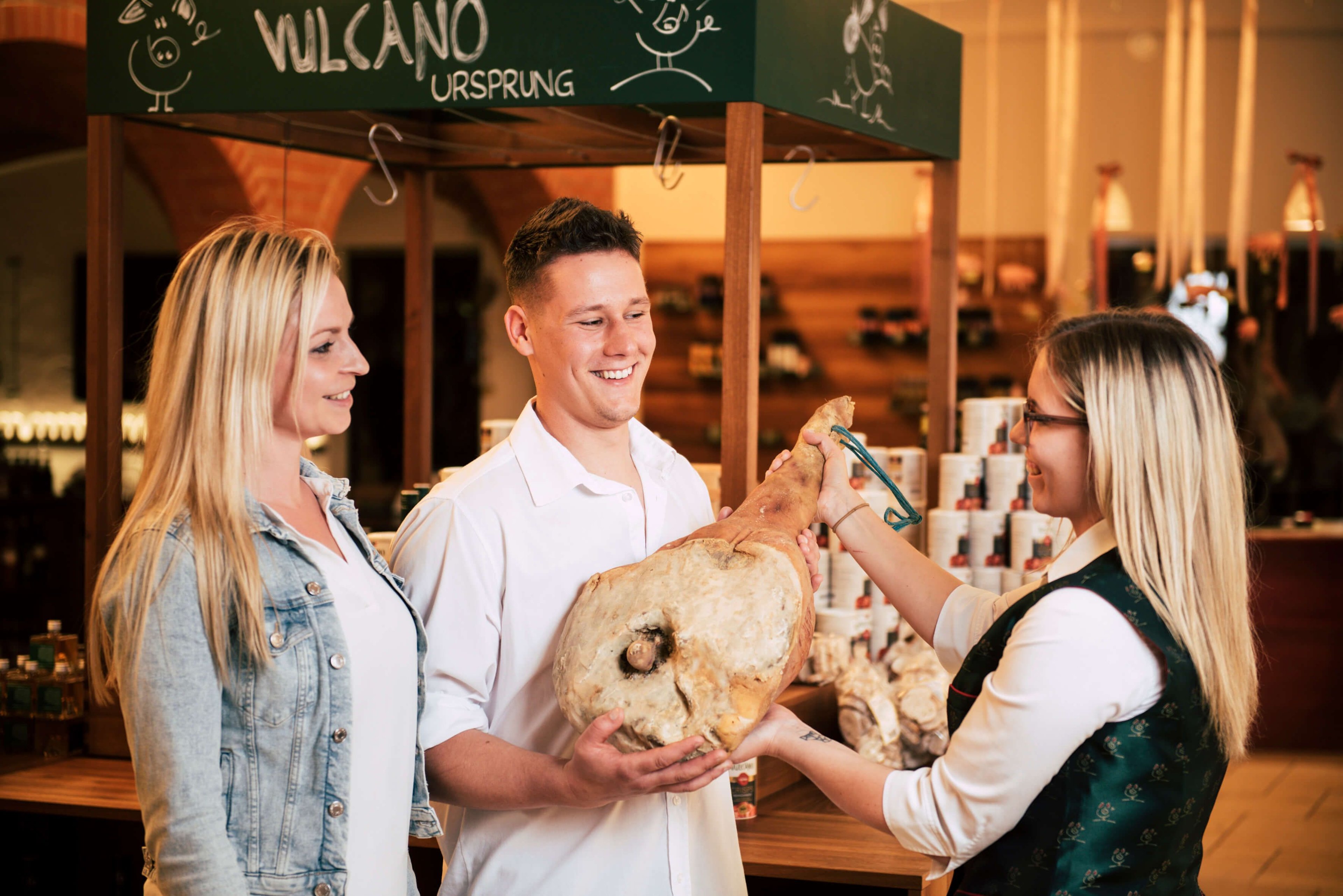 A couple is presented with a piece of ham by a sales clerk.