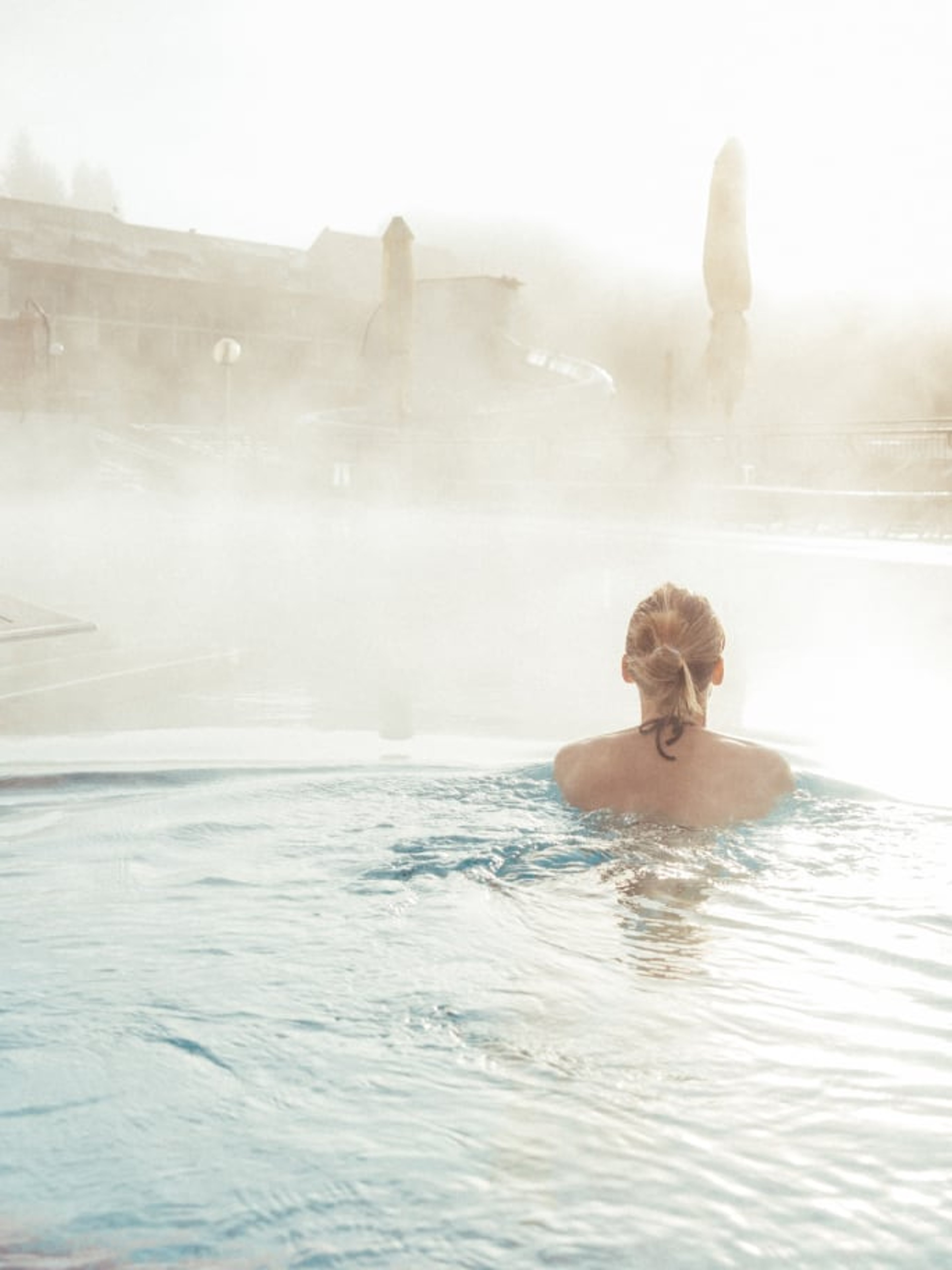 Frau schwimmt im Wasser des Thermenbades. 