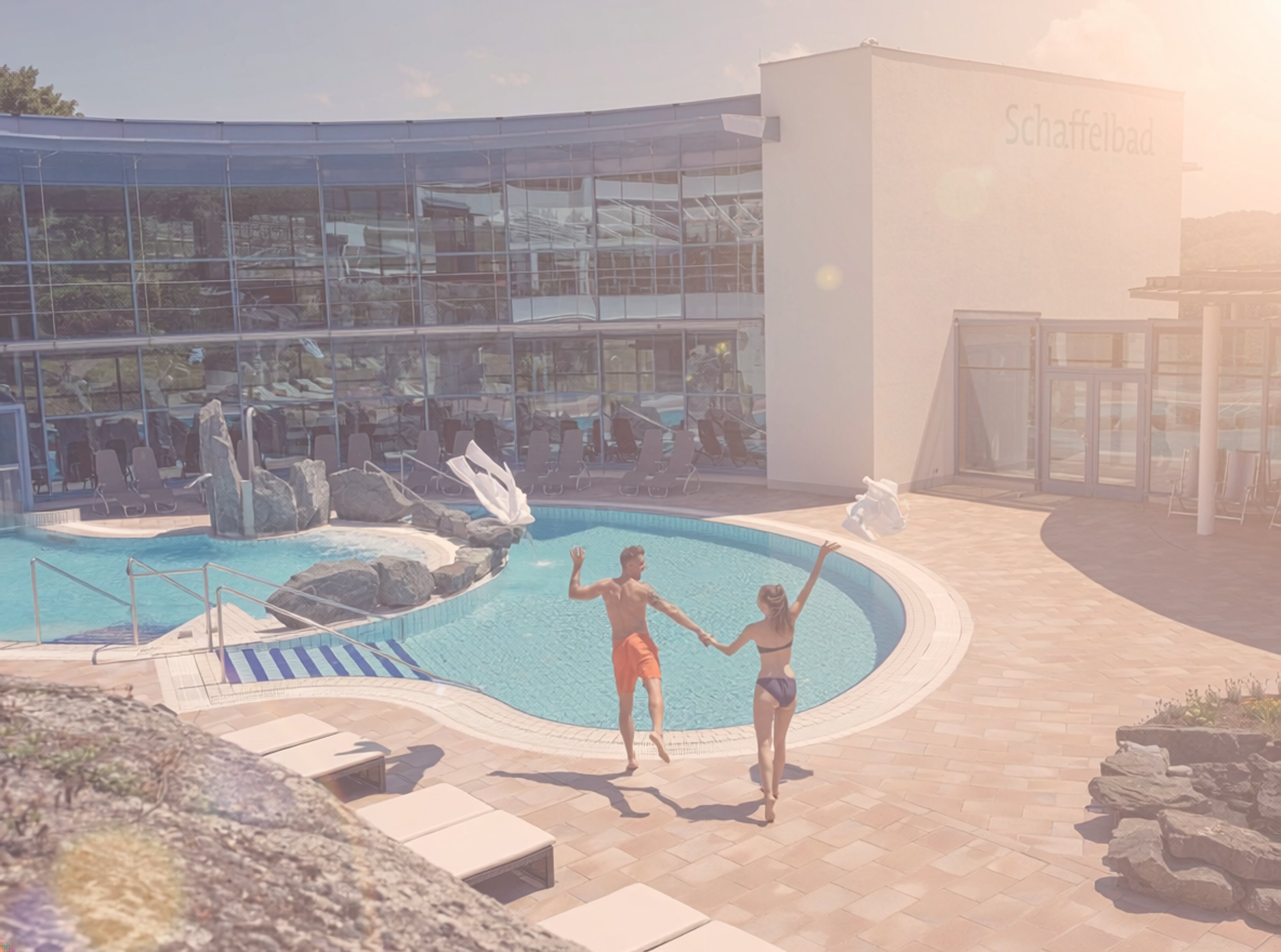 Pärchen die ihre Bademäntel in die Luft werfen und ins Sommerbecken des Felsenbades springen.