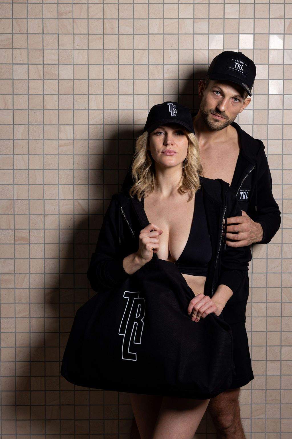 The couple are wearing casual black outfits - woman and man in the sweater jacket - both adorned with the elegant Thermenresort Loipersdorf branding. A harmonious look for shared wellness moments.