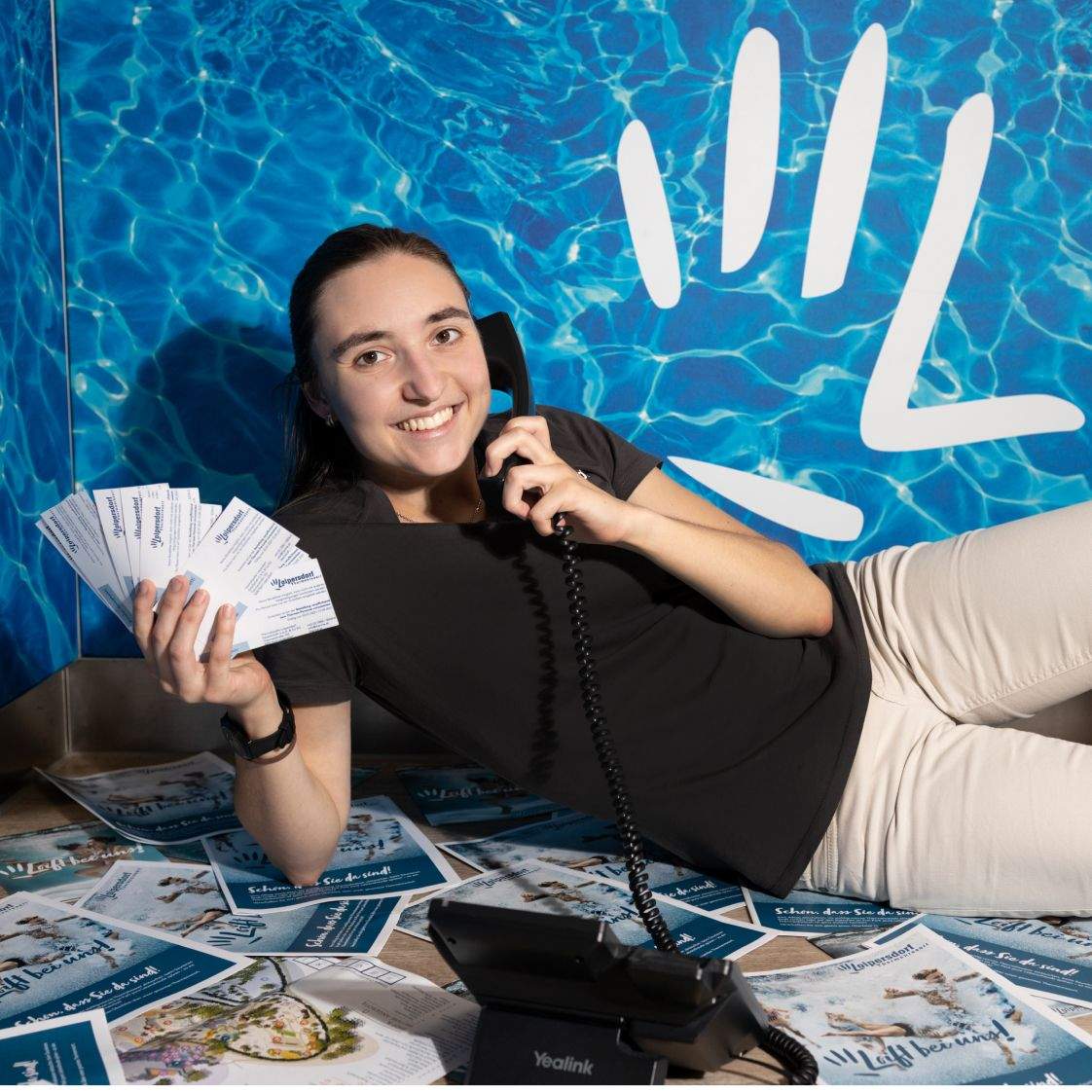 Eine Dame beantwortet einen Anruf und bietet Broschüren an.