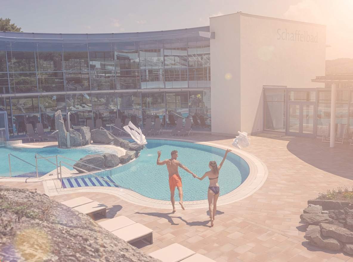 Pärchen die ihre Bademäntel in die Luft werfen und ins Sommerbecken des Felsenbades springen.