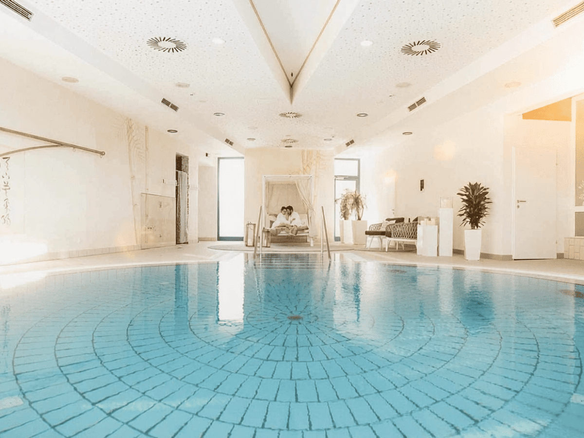 Ein Pool und Himmelbett mit einem Pärchen im Private Spa des Thermenresorts Loipersdorf.