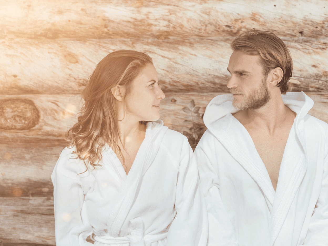 Ein Paar sitzt im Bademantel und schaut sich an.