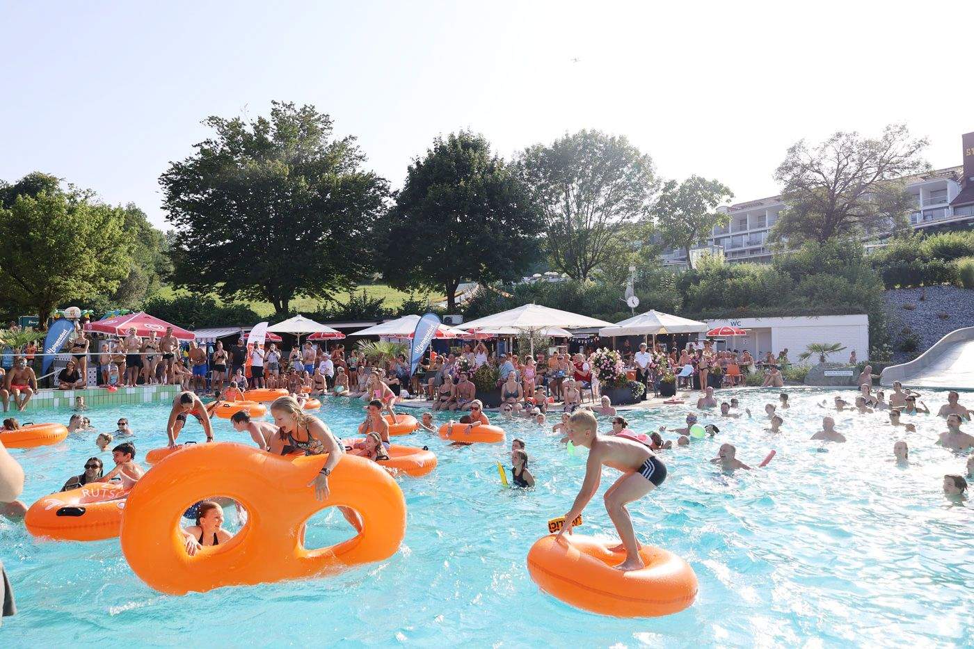 Kinder auf aufblasbaren Schwimmbrezeln im Acapulco Becken