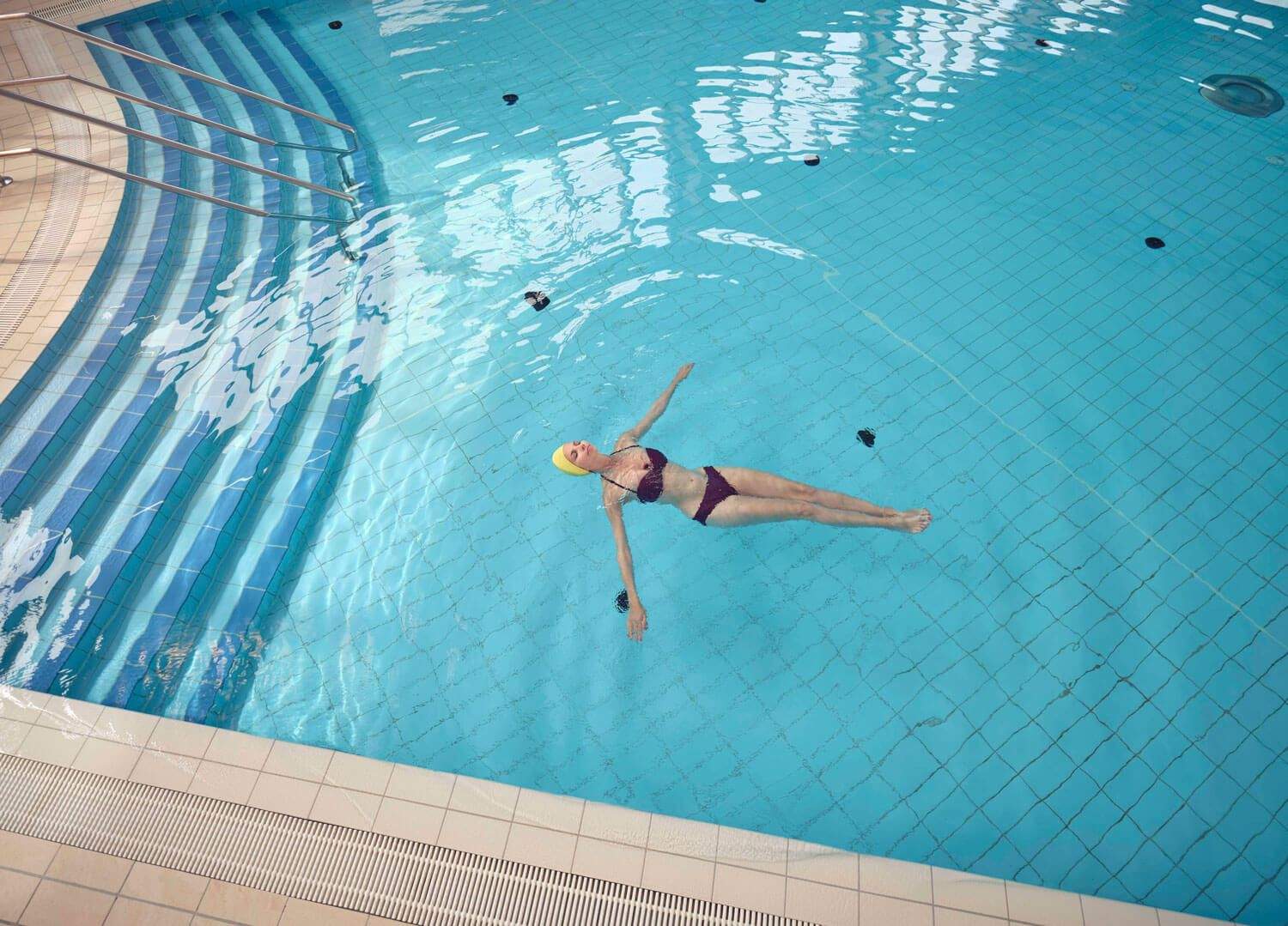 Frau ist im Thermalinnenbecken und lässt sich treiben