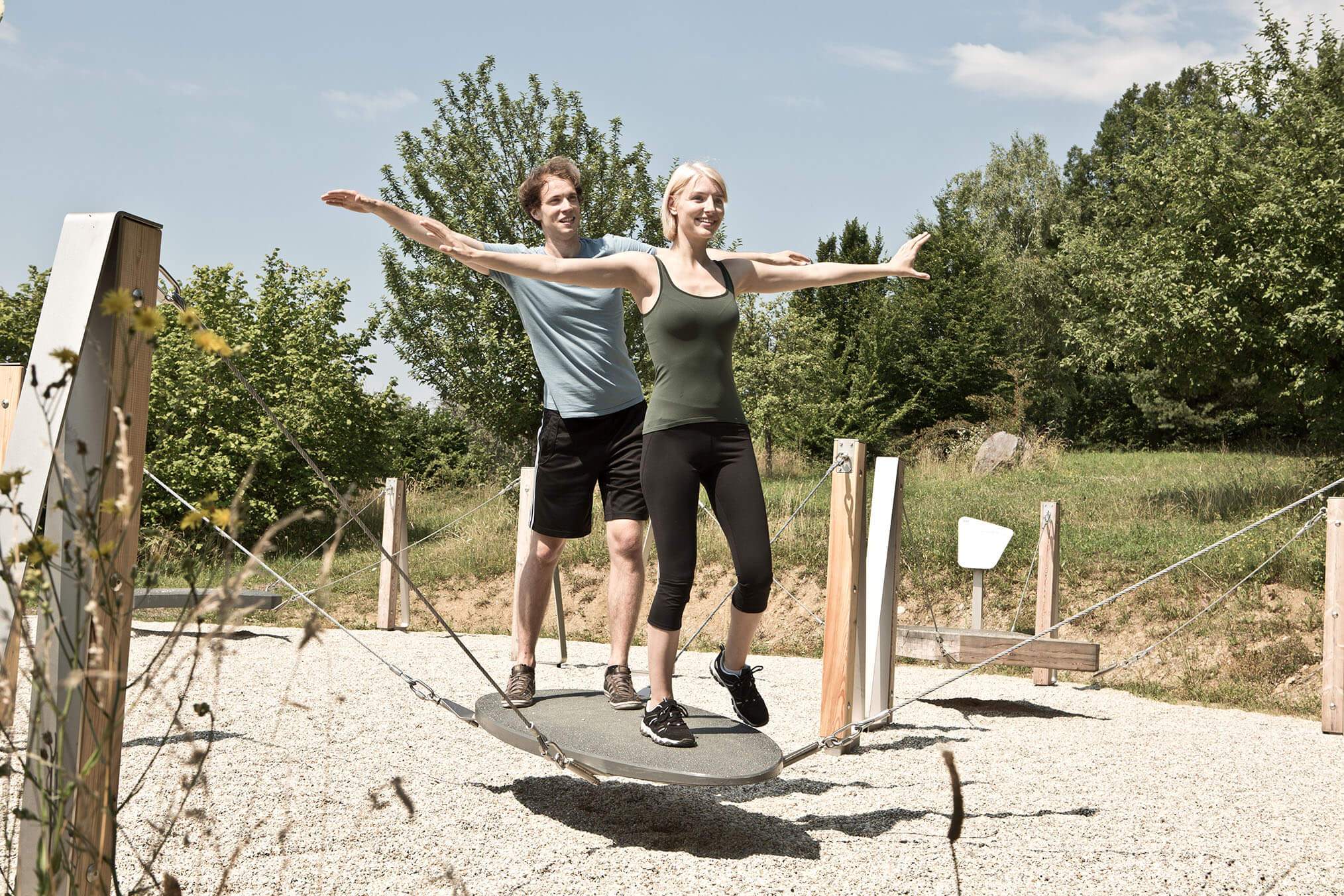 2 people keep their balance on the surfboard on the motor skills trail.
