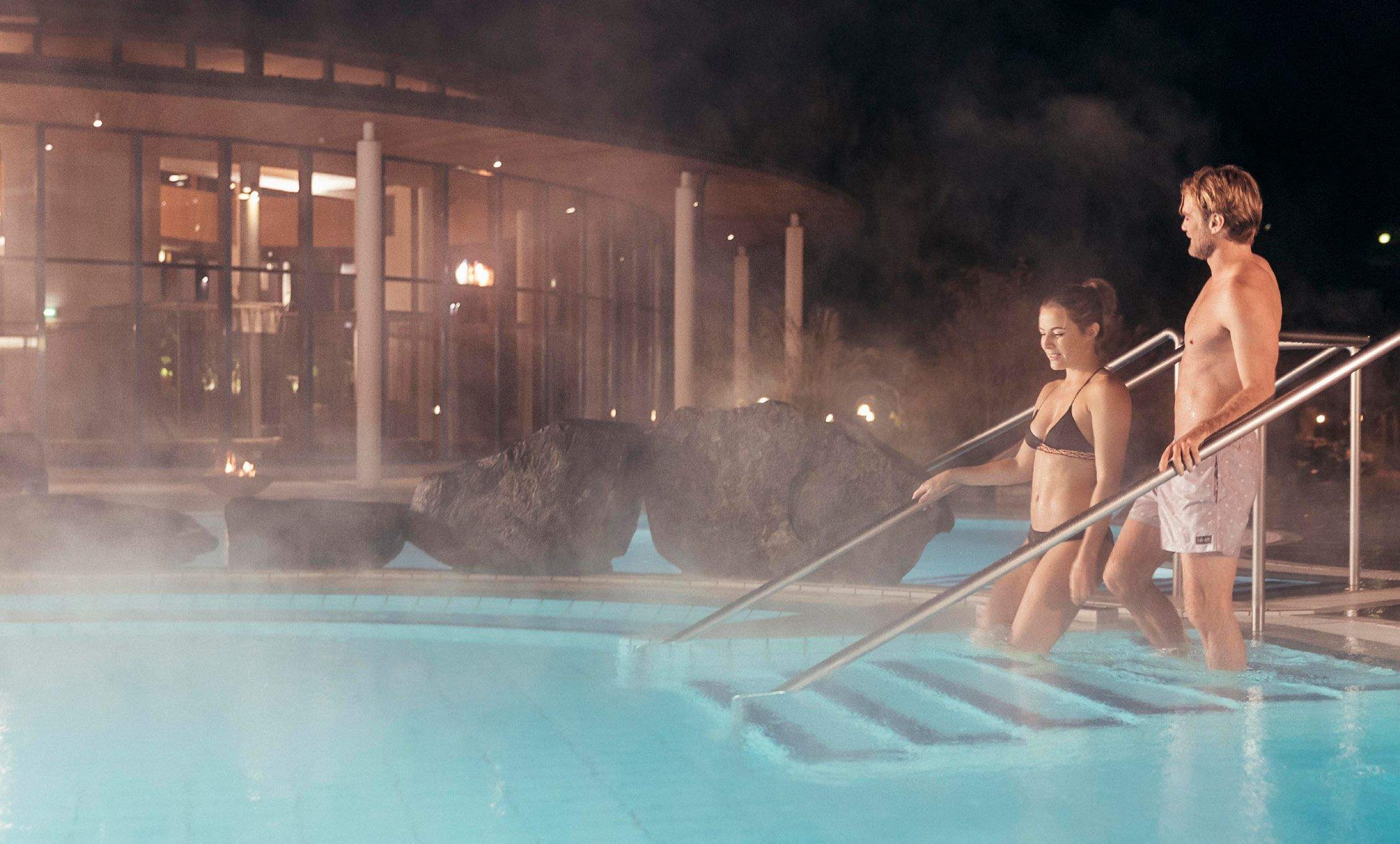 Couple walks together down the stairs in the Schaffelbad into the pleasantly warm thermal water.