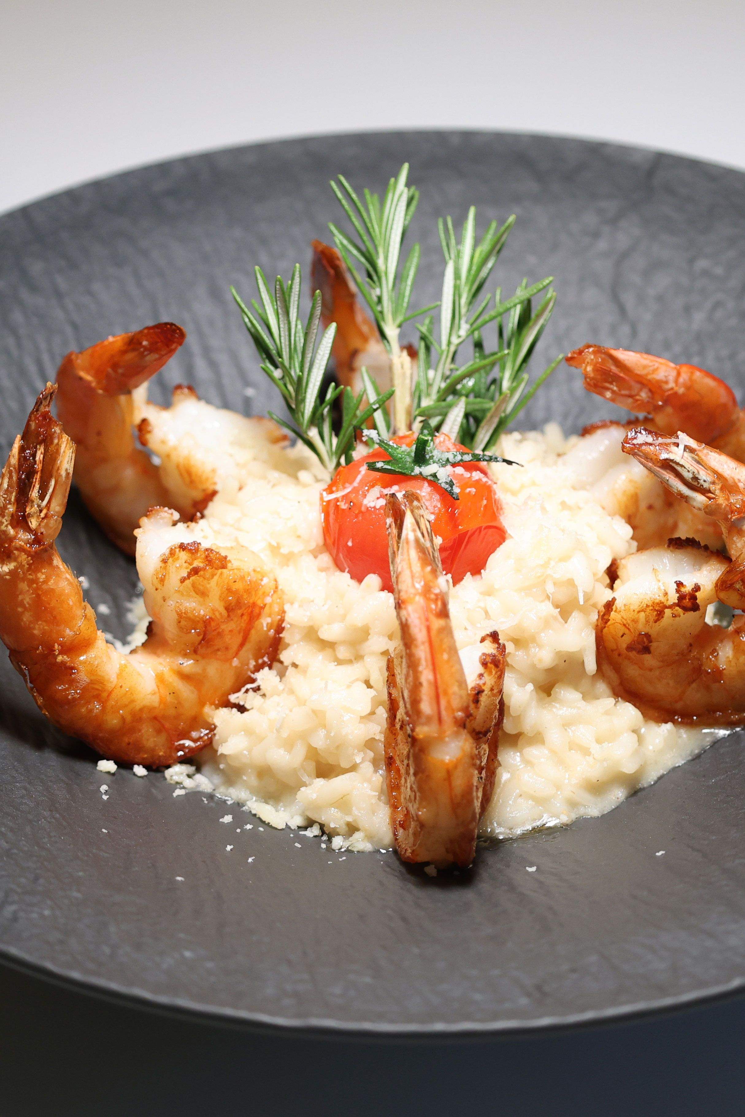 Creamy risotto with seafood on a black plate. 