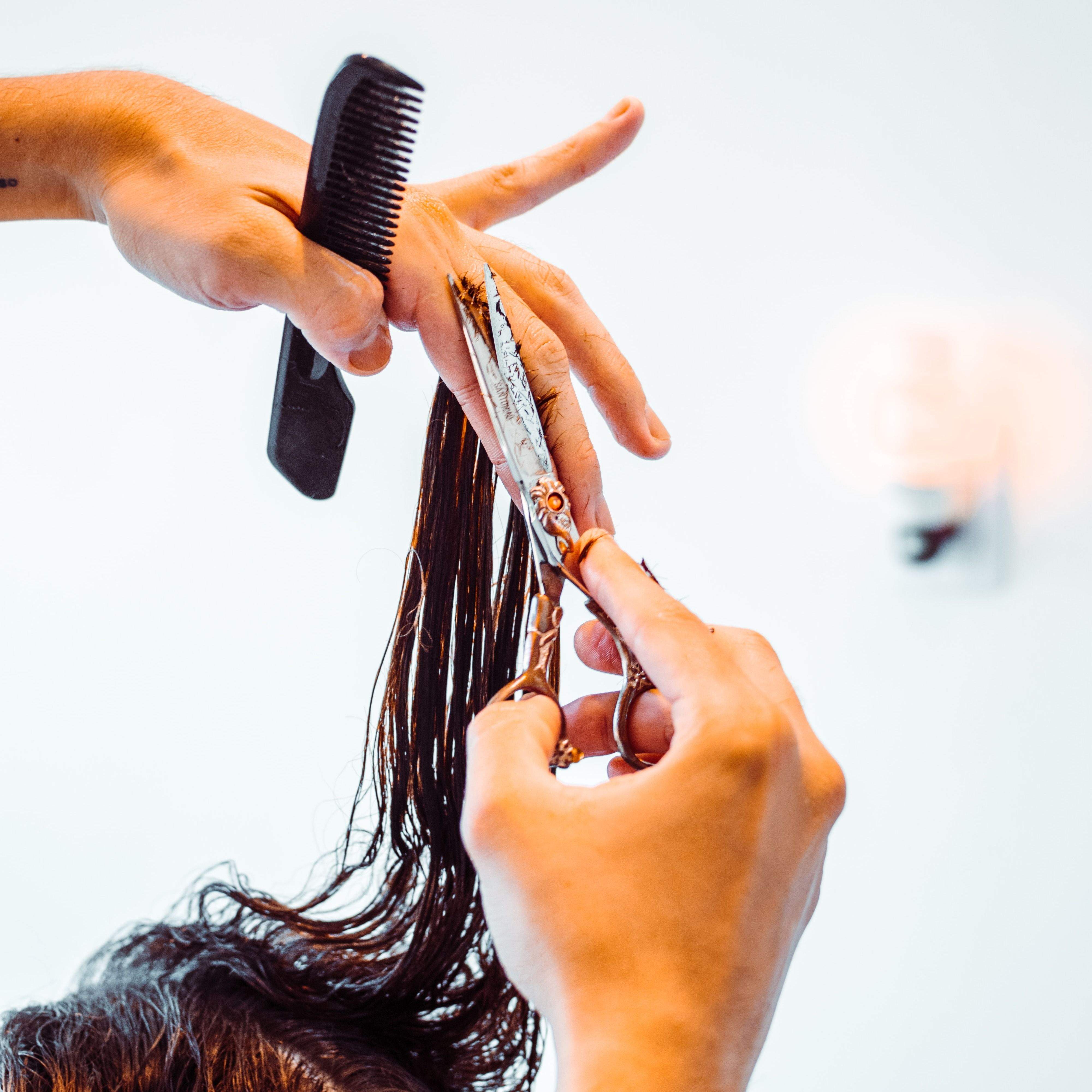 Friseur der einem Gast die Haare schneidet.