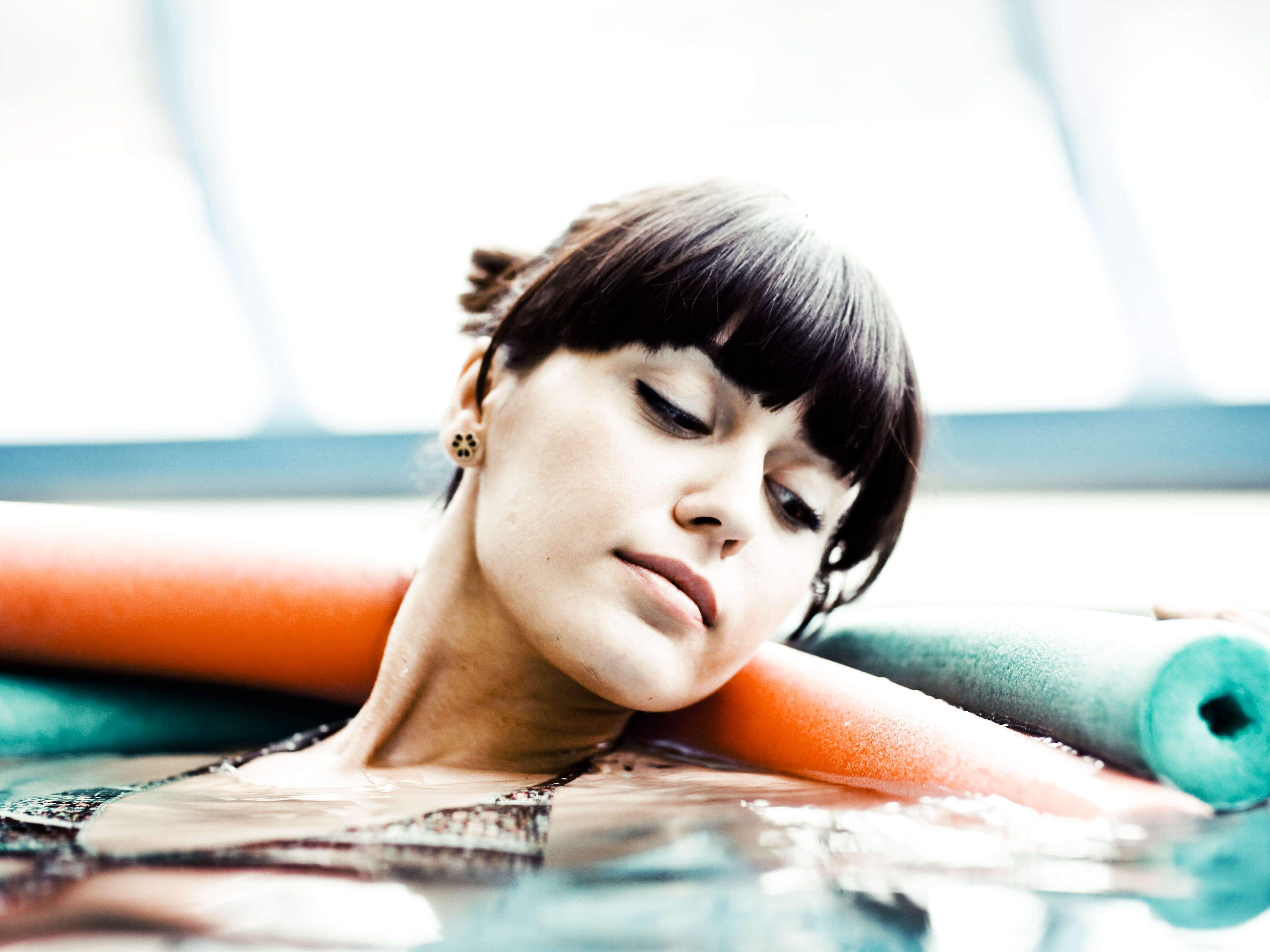 Frau die im Thermalbecken Sportgymnastik macht. 