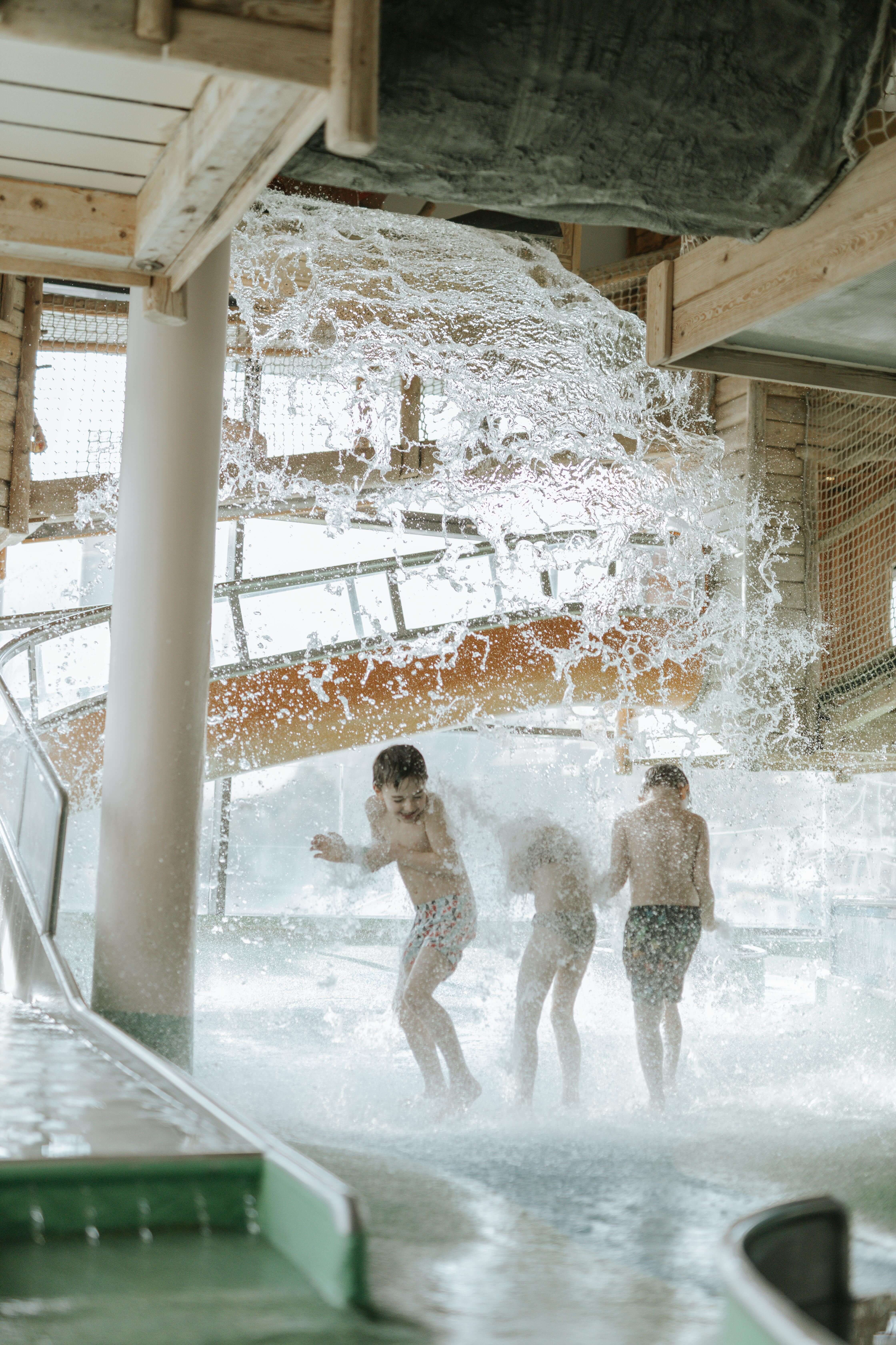Kinder im Wasserspielpark die von der Kürbisdusche von oben Nass gemacht werden.