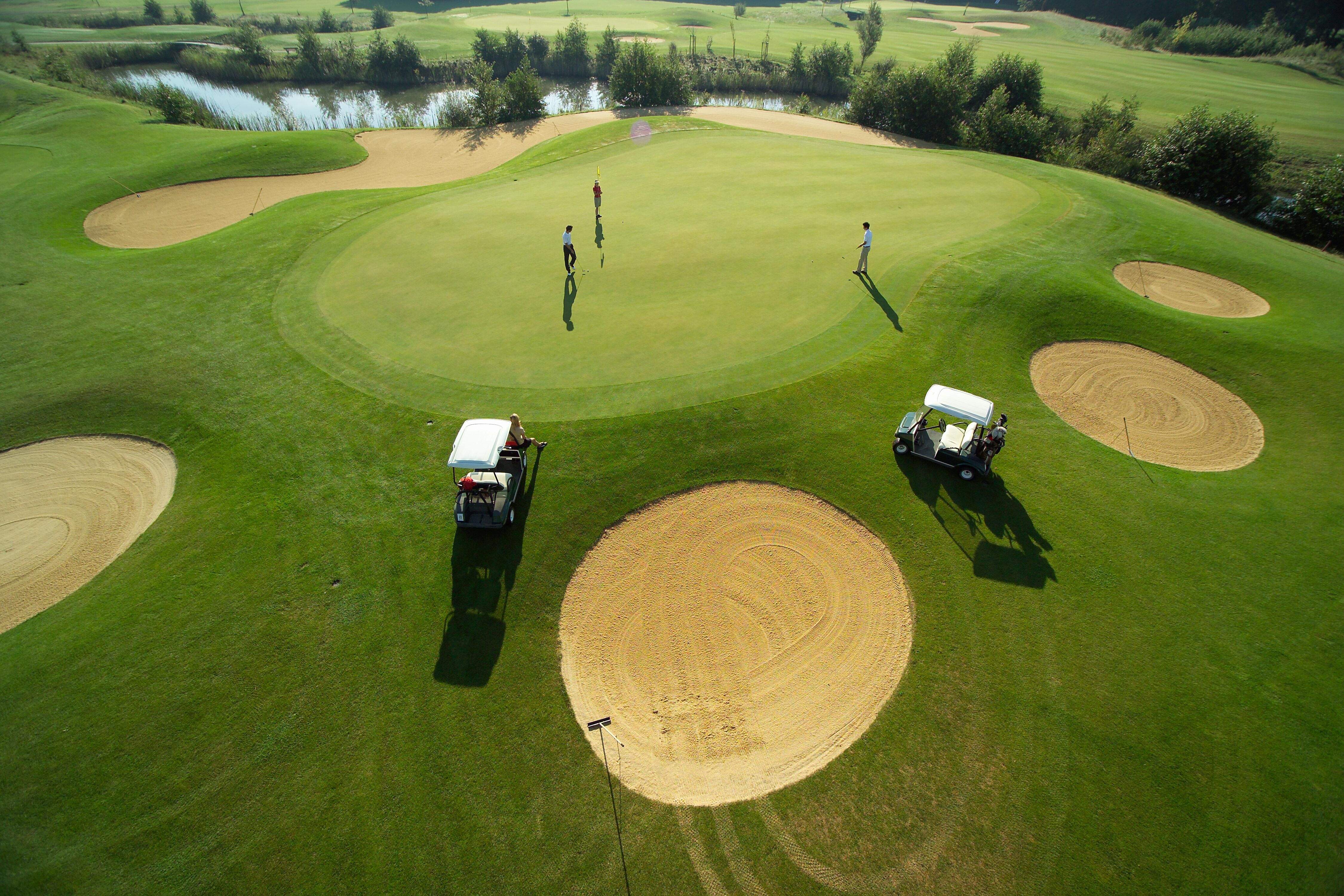 Golfplatz von oben, 2 Golfcarts und Spieler.