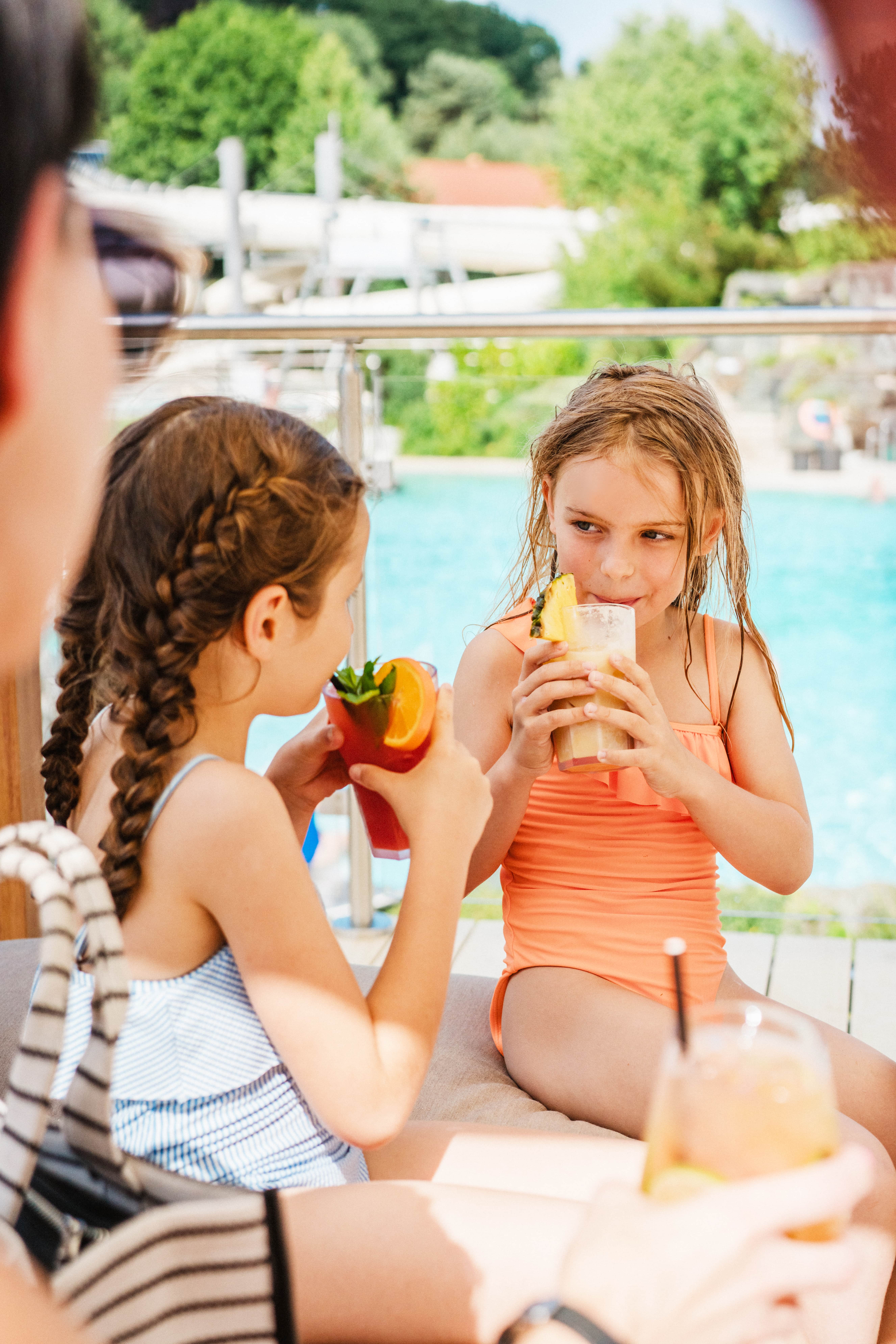 Zwei Mädchen in Badebekleidung trinken bunte Cocktails auf der Rooftop Lounge in der Therme Loipersdorf.