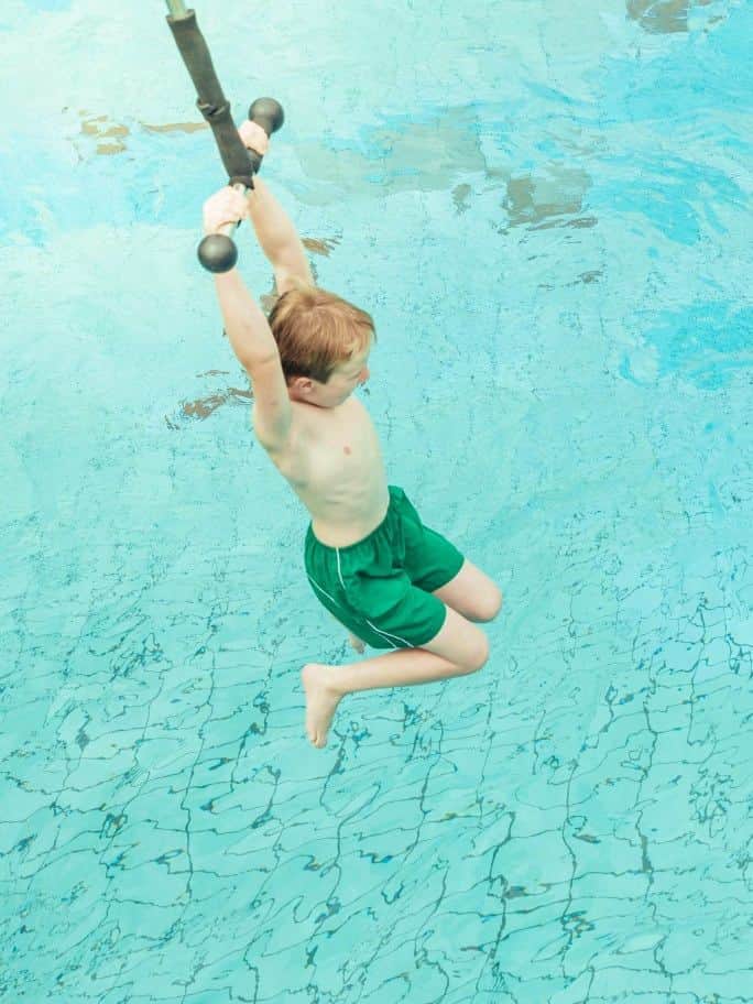 Kind schwingt an der Affenschaukel übers Wellenbecken