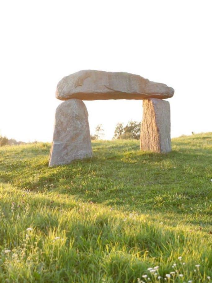 Ein Steinbogen inmitten grüner Hügel.