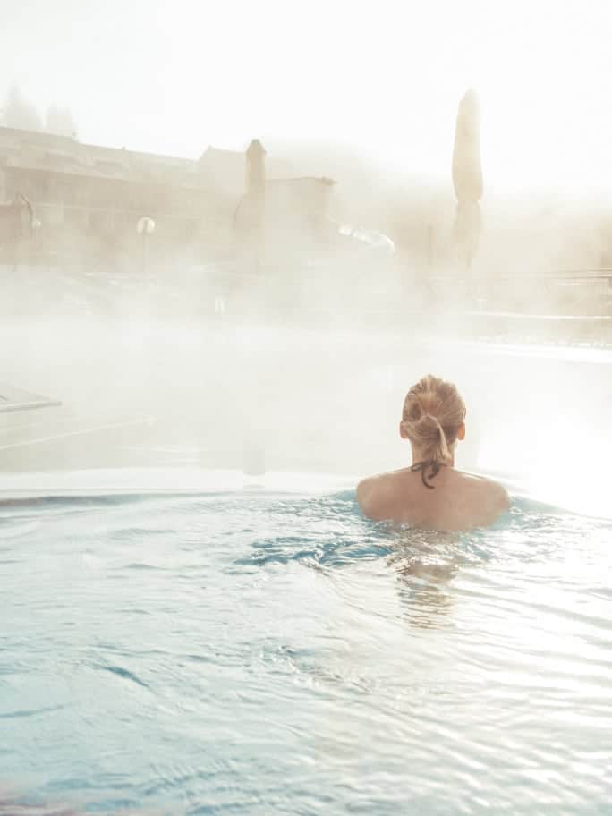 Frau schwimmt im Wasser des Thermenbades.