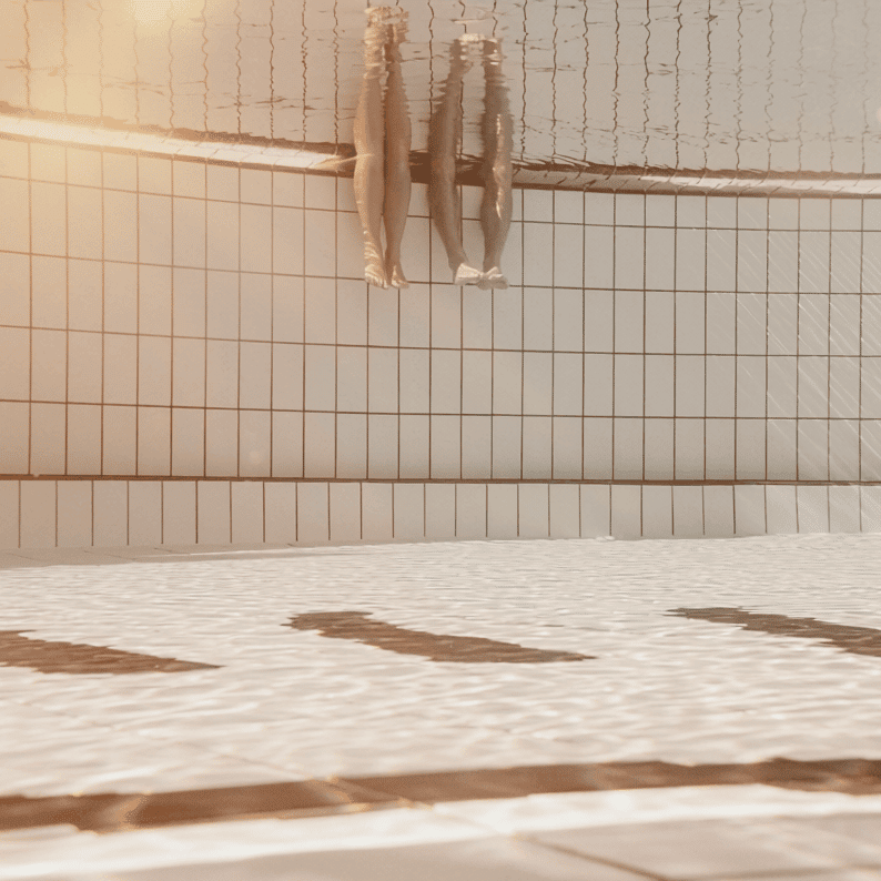 Two people are dipping their legs in the water.